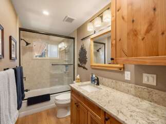 This charming bathroom features a spacious vanity with a granite countertop and ample wooden cabinetry, perfect for storage.