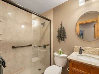 This bathroom features a spacious walk-in shower with a glass door and grab bars for accessibility.