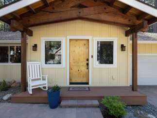 Charming yellow home with a rustic wooden front door and a welcoming porch.