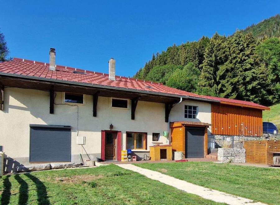 Discover this charming property nestled against a lush green hillside, offering a serene mountain retreat.