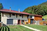 Discover this charming property nestled against a lush green hillside, offering a serene mountain retreat.