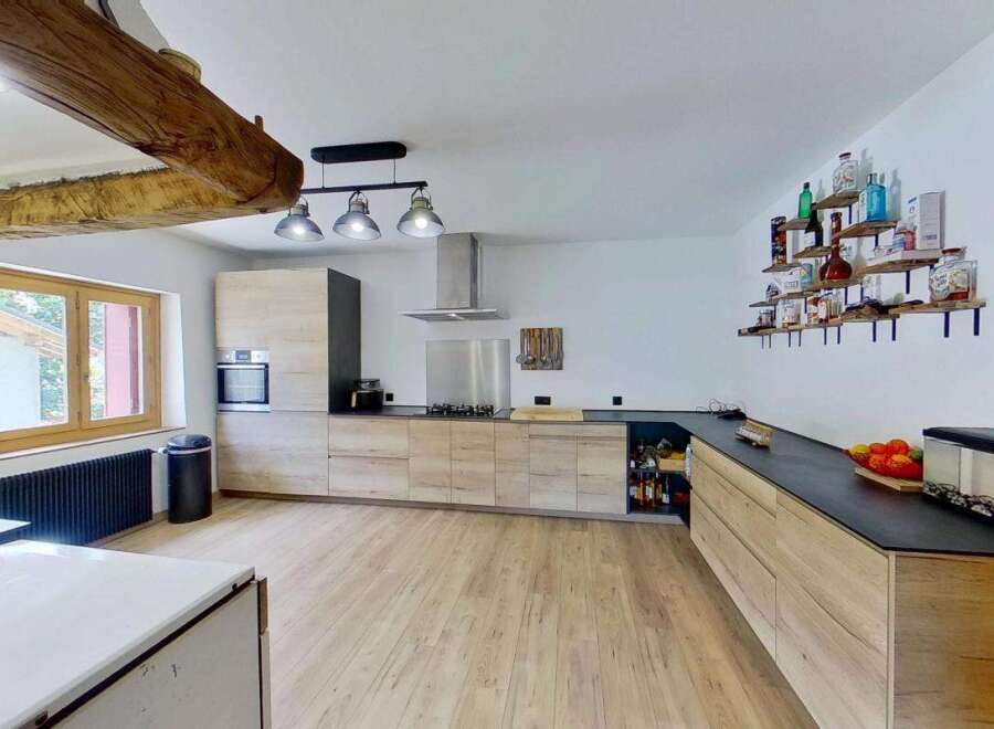 Discover this stunning modern kitchen featuring sleek, light wood cabinetry and a spacious black countertop.