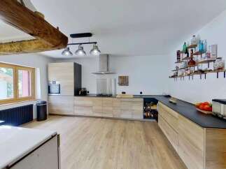 Discover this stunning modern kitchen featuring sleek, light wood cabinetry and a spacious black countertop.