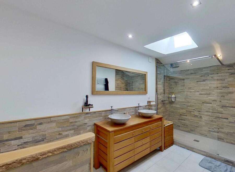 Experience modern luxury in this stunning bathroom featuring a spacious walk-in shower with elegant stone tile accents.