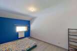 Discover this charming bedroom featuring a vibrant blue accent wall and a comfortable bed with a colorful duvet.