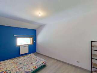 Discover this charming bedroom featuring a vibrant blue accent wall and a comfortable bed with a colorful duvet.