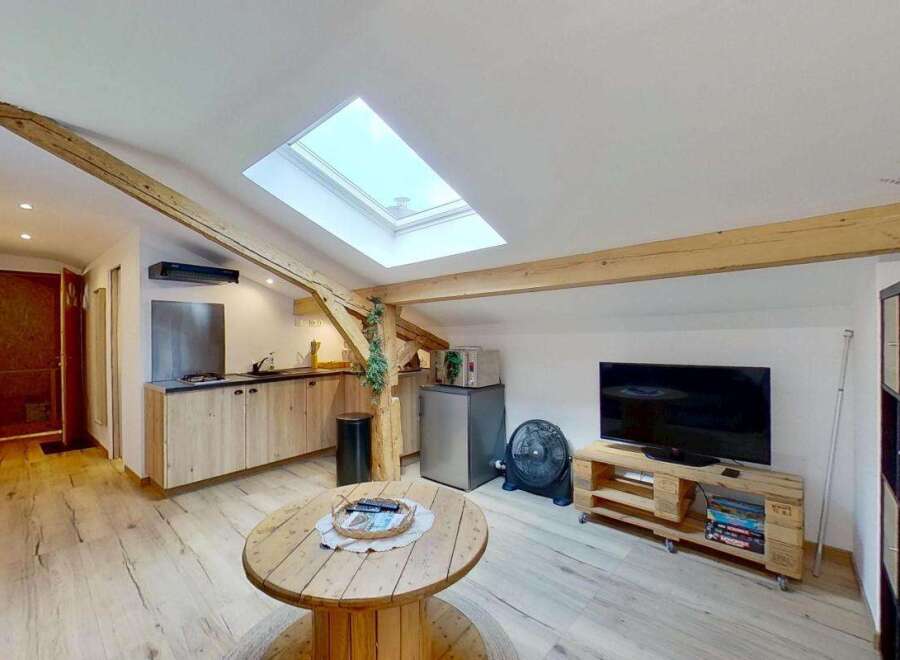 Discover this charming attic apartment featuring exposed wooden beams and a bright skylight, creating a warm and inviting atmosphere.