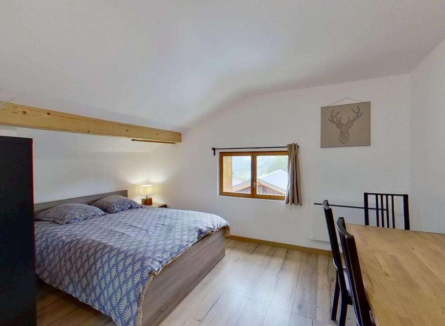 Discover this charming bedroom featuring a comfortable bed with patterned bedding and a bedside lamp for a cozy ambiance.
