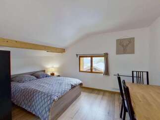 Discover this charming bedroom featuring a comfortable bed with patterned bedding and a bedside lamp for a cozy ambiance.
