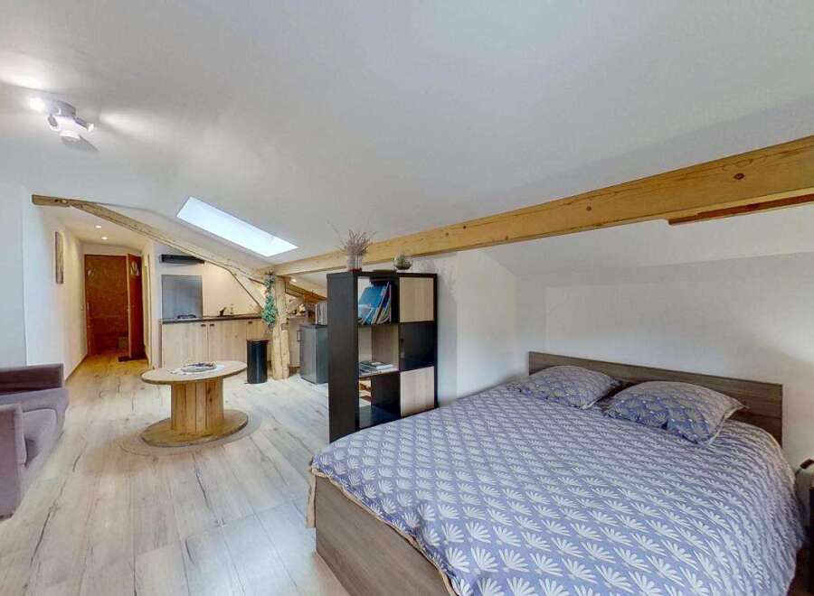 Discover this charming studio apartment featuring a cozy living area with a comfortable sofa and a unique wooden spool coffee table.