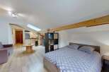 Discover this charming studio apartment featuring a cozy living area with a comfortable sofa and a unique wooden spool coffee table.