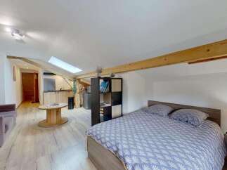 Discover this charming studio apartment featuring a cozy living area with a comfortable sofa and a unique wooden spool coffee table.