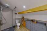 Discover this charming bathroom featuring a spacious walk-in shower with modern grey tiling and a rainfall showerhead.