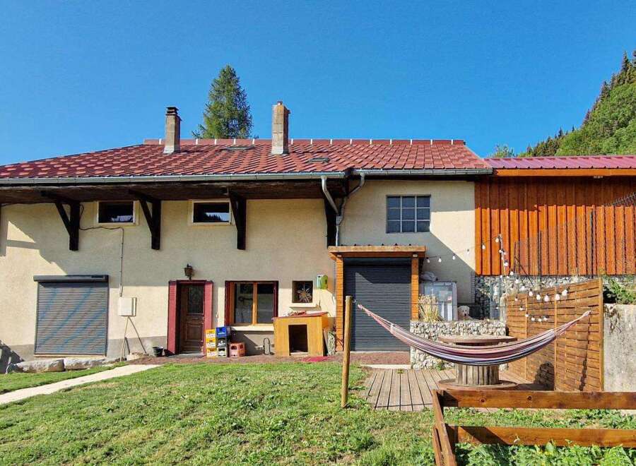 Discover this charming property featuring a spacious house with a red tile roof and a rustic wooden extension.