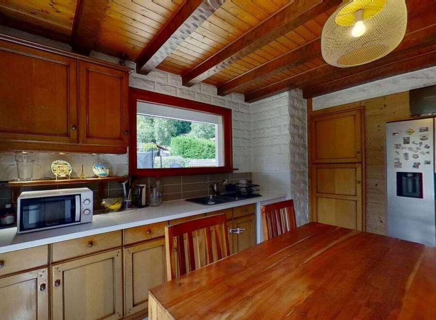 Discover this charming kitchen featuring warm wooden cabinetry and a rustic beamed ceiling.
