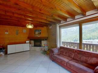 Experience cozy mountain living in this charming living room featuring a rustic stone fireplace and warm wood-paneled walls.