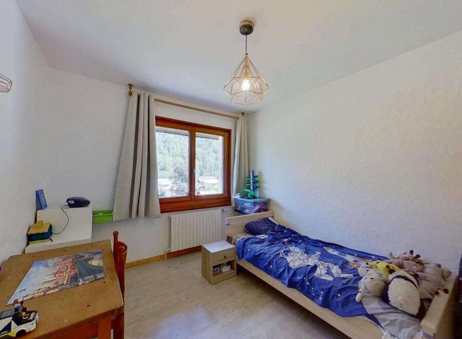 Discover this charming bedroom featuring a cozy single bed with playful bedding and a collection of stuffed animals.