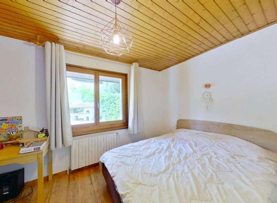 This charming bedroom features a cozy bed with white linens, perfect for relaxation.