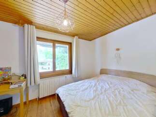 This charming bedroom features a cozy bed with white linens, perfect for relaxation.
