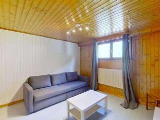Experience cozy living in this charming room featuring a comfortable grey sofa and a modern white coffee table.