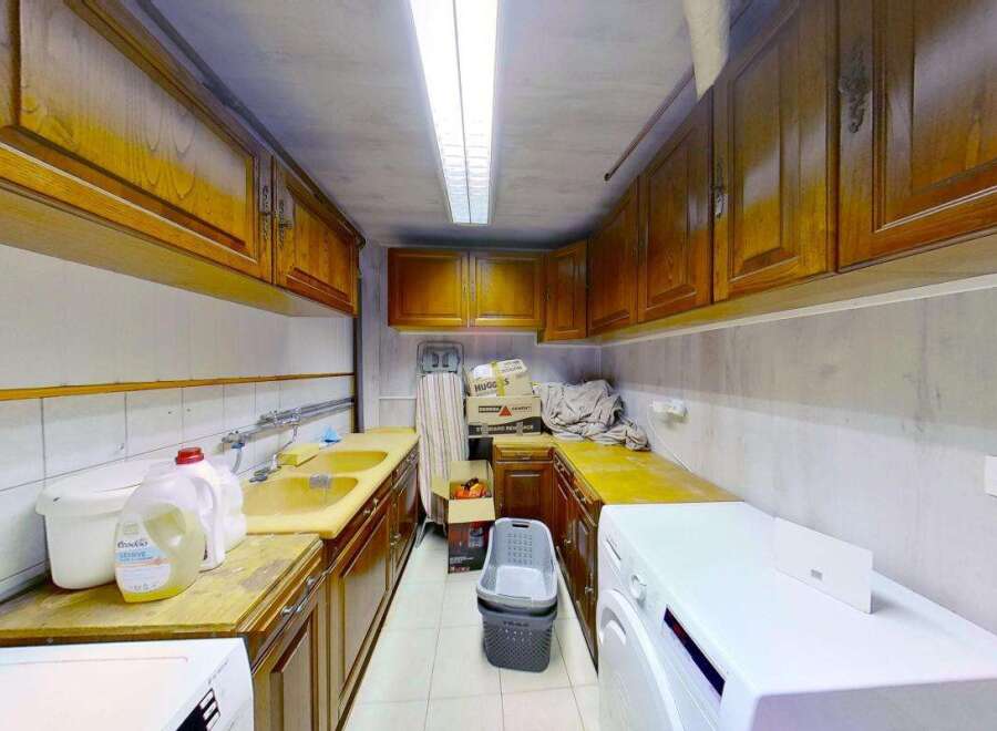 Discover a functional laundry room featuring ample storage with overhead wooden cabinets and a spacious countertop.