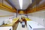 Discover a functional laundry room featuring ample storage with overhead wooden cabinets and a spacious countertop.