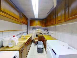 Discover a functional laundry room featuring ample storage with overhead wooden cabinets and a spacious countertop.