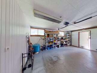 Discover ample storage solutions in this versatile garage space, featuring multiple shelving units perfect for organizing tools, sports equipment, and seasonal items.