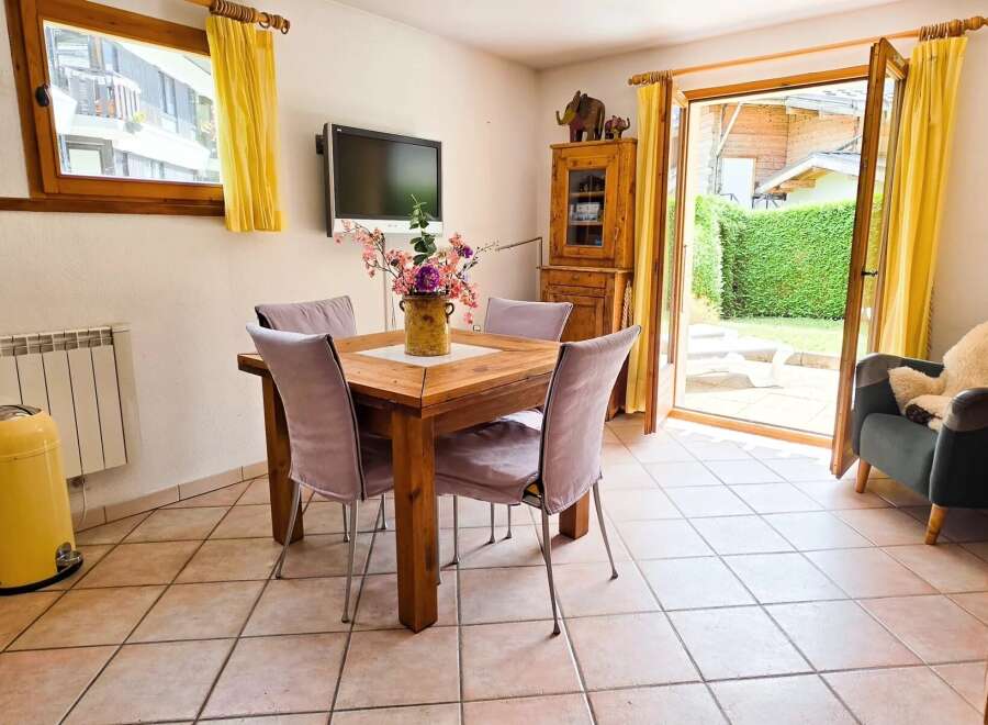 Enjoy meals with a view in this charming dining area, featuring a rustic wooden table and comfortable upholstered chairs.