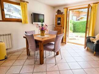 Enjoy meals with a view in this charming dining area, featuring a rustic wooden table and comfortable upholstered chairs.