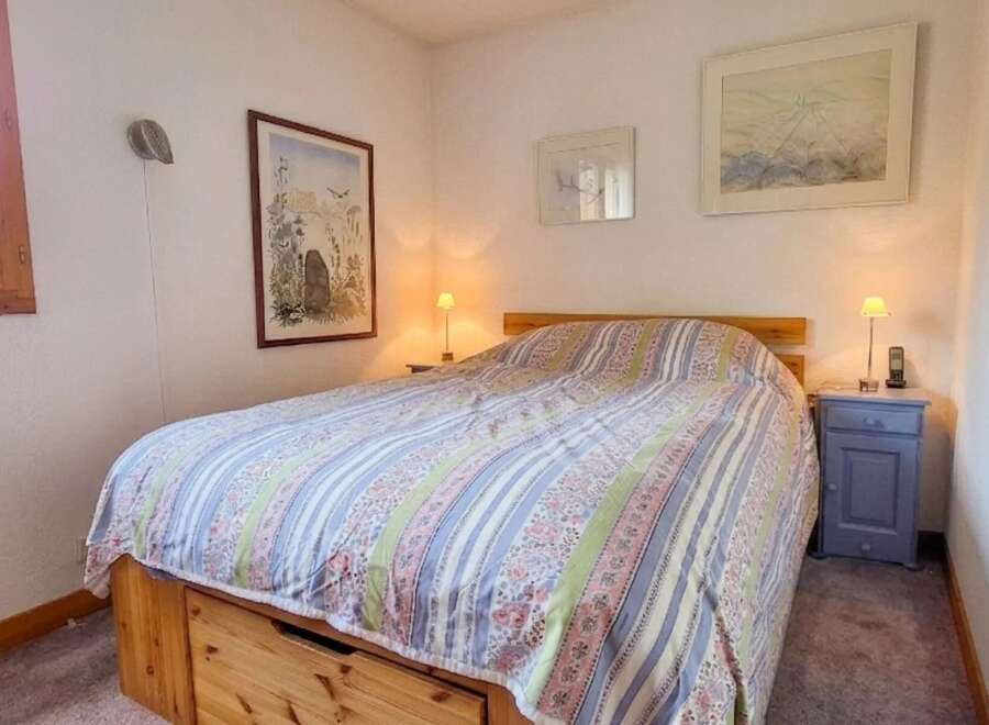 This charming bedroom features a comfortable bed adorned with a colorful, patterned comforter.