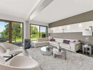 Experience modern living in this spacious living room, featuring a luxurious white sectional sofa and unique sculptural armchairs.