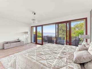 Experience luxurious living in this stunning bedroom featuring a large, comfortable bed and a modern entertainment center.