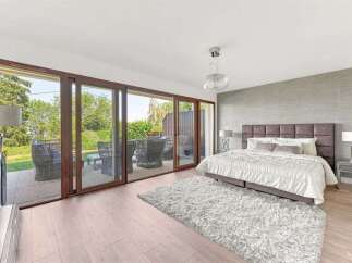 Experience luxurious living in this master bedroom, featuring a king-size bed with a plush headboard and a soft, inviting rug.