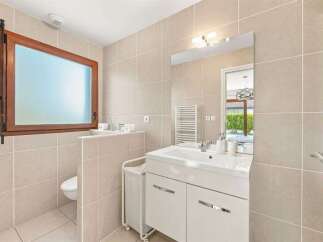 This modern bathroom features a sleek white vanity with ample storage and a large mirror, perfect for your morning routine.