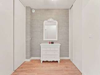 This hallway features a charming white dresser with a decorative mirror, perfect for adding a touch of elegance to your home.