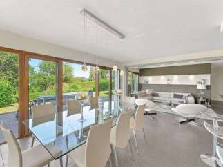 Experience modern living in this spacious open-concept home, featuring a sleek glass dining table and elegant pendant lighting.