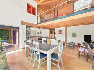 Experience rustic charm in this spacious open-concept living area, featuring a soaring wooden-beamed ceiling and a loft overlooking the main floor.