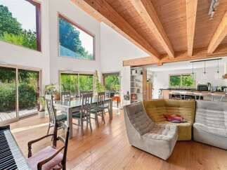 Experience modern living in this stunning home featuring a spacious open-concept living and dining area with soaring ceilings and exposed wooden beams.