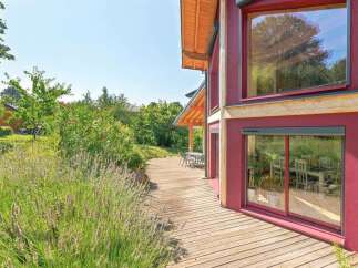 Experience modern living in this stunning home featuring a striking red exterior and expansive windows that flood the interior with natural light.