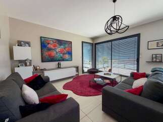 Experience modern living in this stylish living room, featuring comfortable charcoal sofas adorned with vibrant red and black accent pillows.