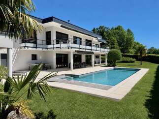 Experience luxury living in this modern white villa featuring a stunning rectangular swimming pool and a spacious outdoor patio perfect for entertaining.