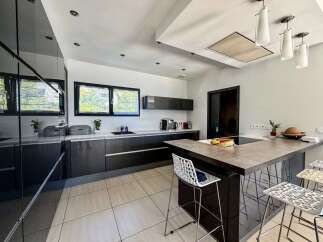 Experience modern living in this sleek kitchen featuring high-gloss dark cabinetry and a spacious island with bar seating.