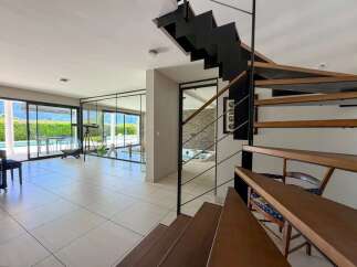 Experience modern luxury in this stunning home featuring a sleek spiral staircase and expansive glass doors that open to a private pool and lush greenery.