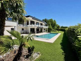 Experience luxury living in this stunning modern villa, featuring a pristine swimming pool and expansive green lawn perfect for relaxation and entertainment.