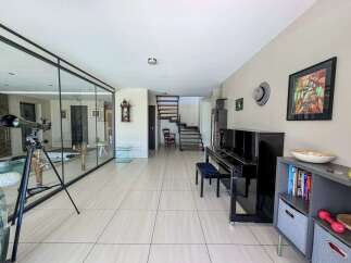 Experience modern living in this spacious home featuring a sleek black piano and a unique glass-enclosed area.