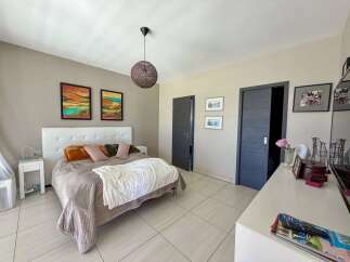 This inviting bedroom features a comfortable queen-size bed with a plush headboard, complemented by decorative pillows and a cozy throw blanket.