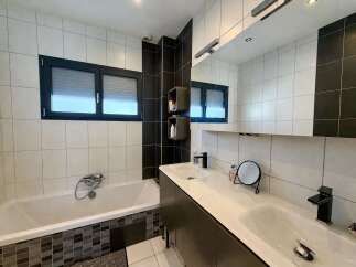 This modern bathroom features a sleek design with a bathtub and a double vanity.