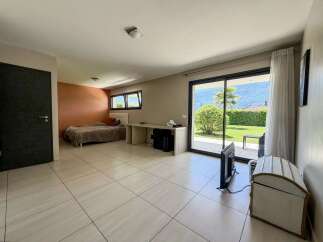 Experience modern living in this spacious bedroom featuring a comfortable bed, a sleek desk area, and large sliding glass doors that open to a beautiful outdoor view.