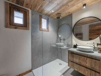 Experience modern alpine living in this stunning bathroom featuring a spacious walk-in shower with sleek grey tiling and a minimalist white shower base.